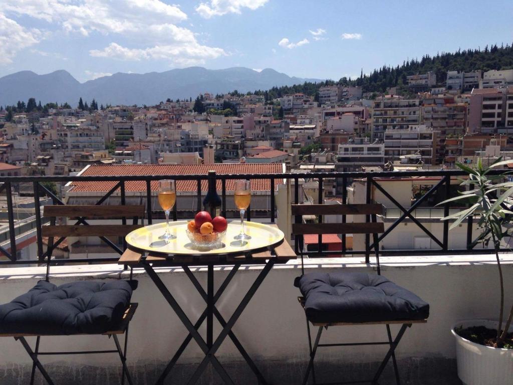 uma mesa com dois copos de vinho numa varanda em Cozy Loft - Best view of the city em Lamía
