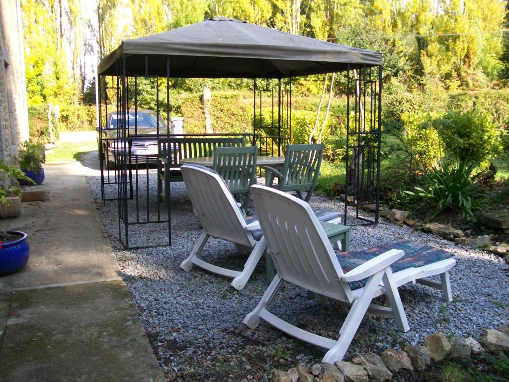 un gruppo di sedie e un tavolo sotto un gazebo di Stone Cottage a Ménéac