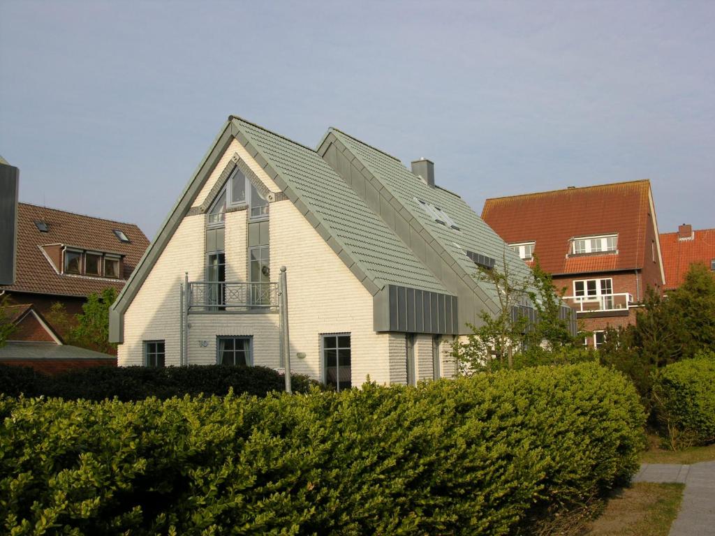 una casa blanca con techo de gambrel en Inselresidenz Seeschwalbe Langeoog, en Langeoog