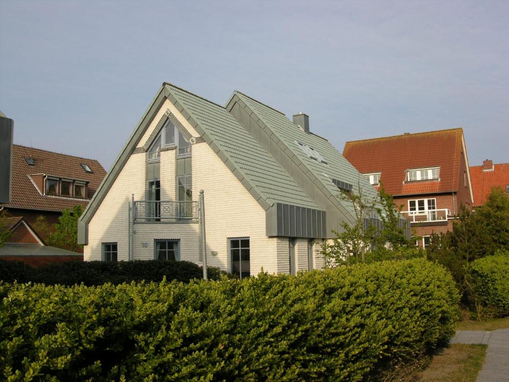 une maison blanche avec un toit en gambrel dans l'établissement Inselresidenz Seeschwalbe Langeoog, à Langeoog