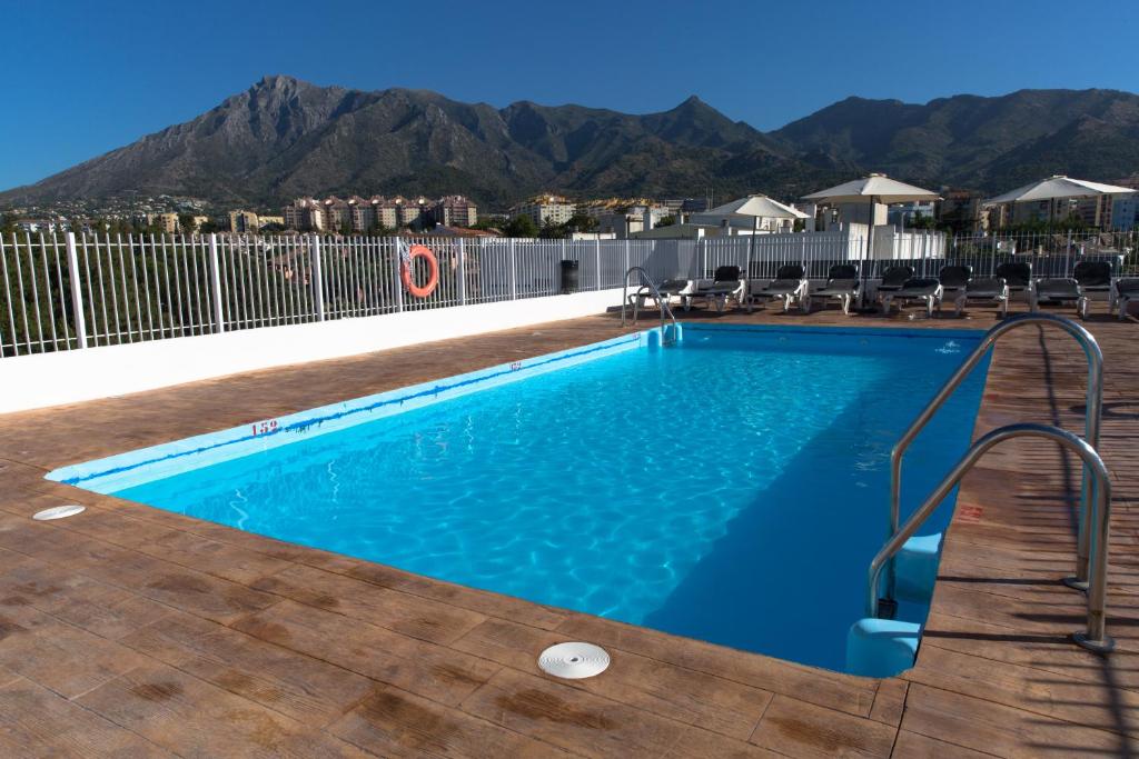 una piscina con sillas y montañas en el fondo en Ona Marbella Inn, en Marbella