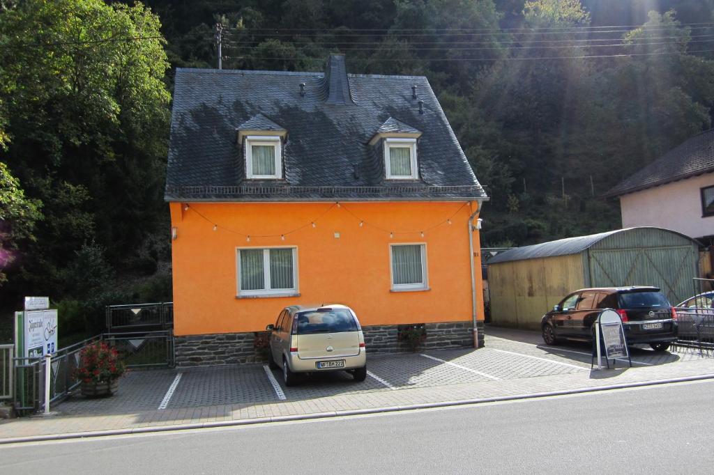 una pequeña casa naranja con autos estacionados frente a ella en Gästehaus Ströter, en Bacharach