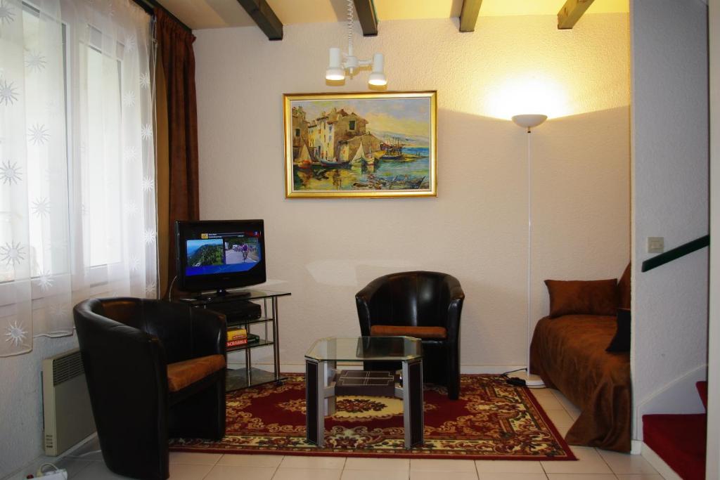 ein Wohnzimmer mit 2 Stühlen, einem Tisch und einem Sofa in der Unterkunft Maison à ROYAN PONTAILLAC in Royan