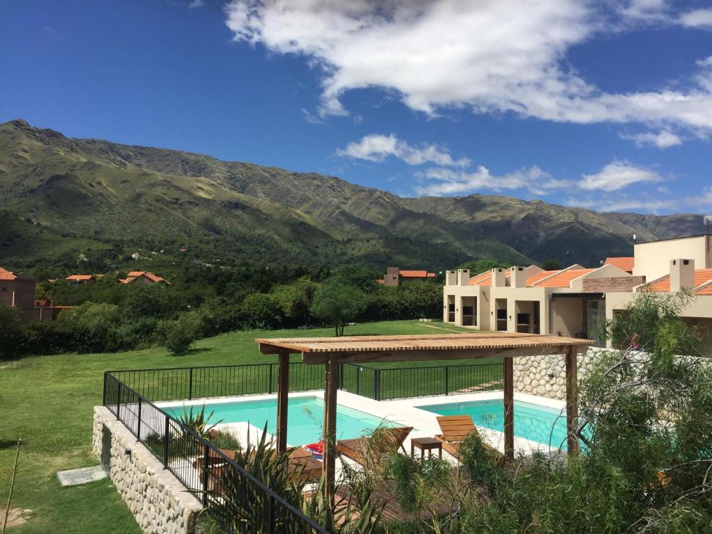 una piscina con cenador y montañas de fondo en Parque Los Nogales Apart Hotel en Merlo