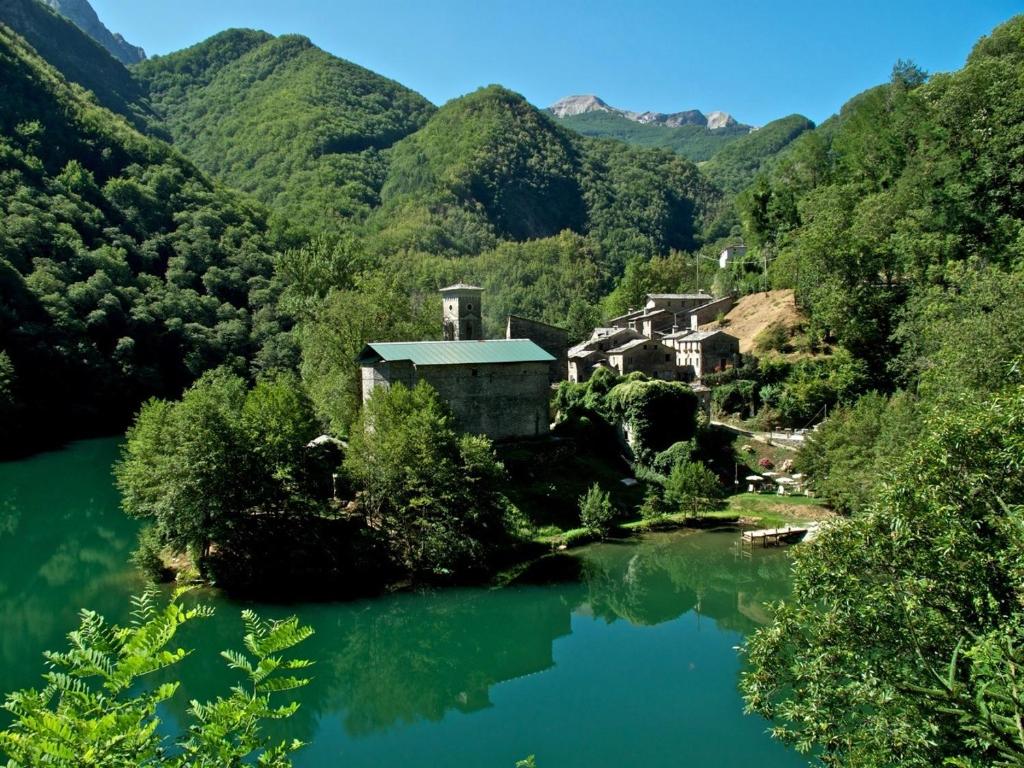 Borgo Isola Santa في Isola Santa: منزل على جانب نهر مع جبال