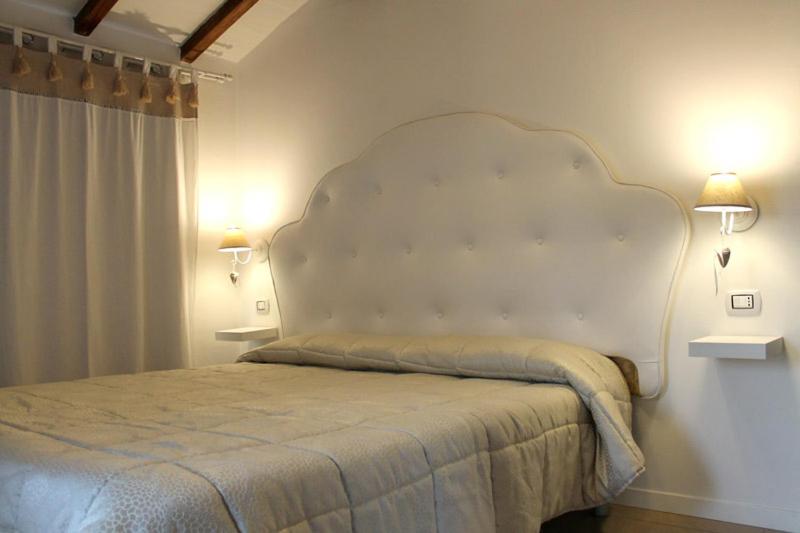 a bed in a bedroom with two lights on the wall at Room & Breakfast A casa di Emma in Ganaceto
