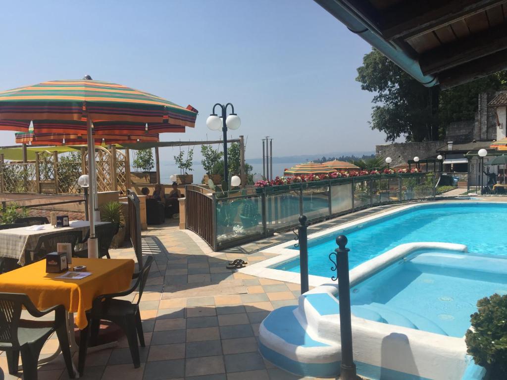 a swimming pool with a table and an umbrella at Garda Sol SPA Hotel & Appartamenti in Toscolano Maderno