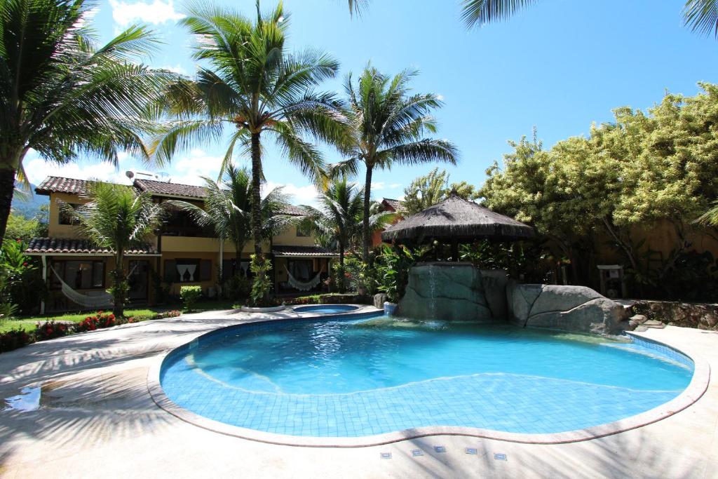 a swimming pool in a resort with palm trees at Casa 31 Paraty in Paraty