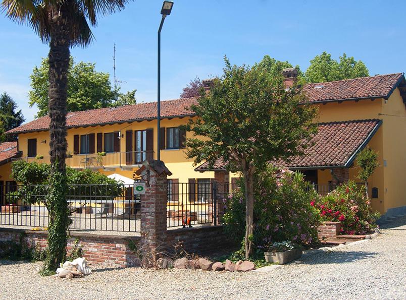 ein gelbes Haus mit einem Zaun und einem Baum in der Unterkunft B&B Cascina Baraggione in Granozzo con Monticello