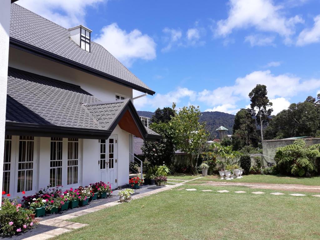 ein weißes Haus mit Blumen im Hof in der Unterkunft Andora Nuwara Eliya in Nuwara Eliya