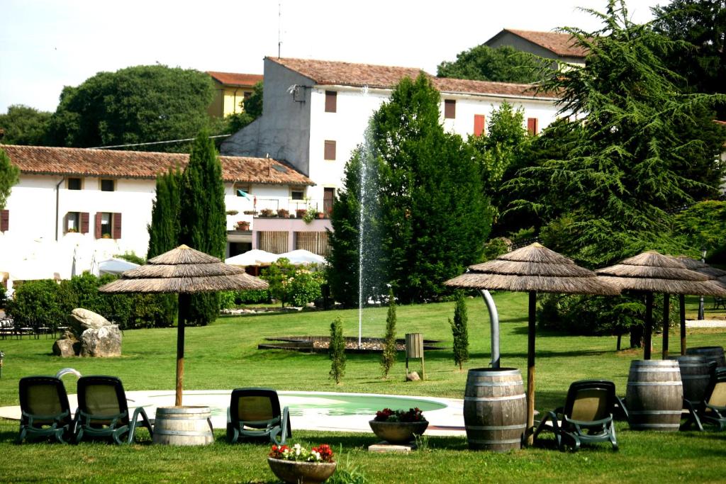a garden with chairs and umbrellas and a swimming pool at Resort La Mola in Sommacampagna