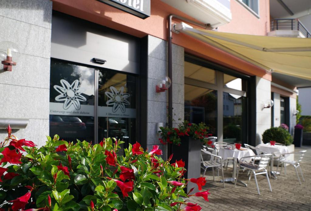 a restaurant with red flowers in front of a building at Hotel Garni Arnegg in Arnegg