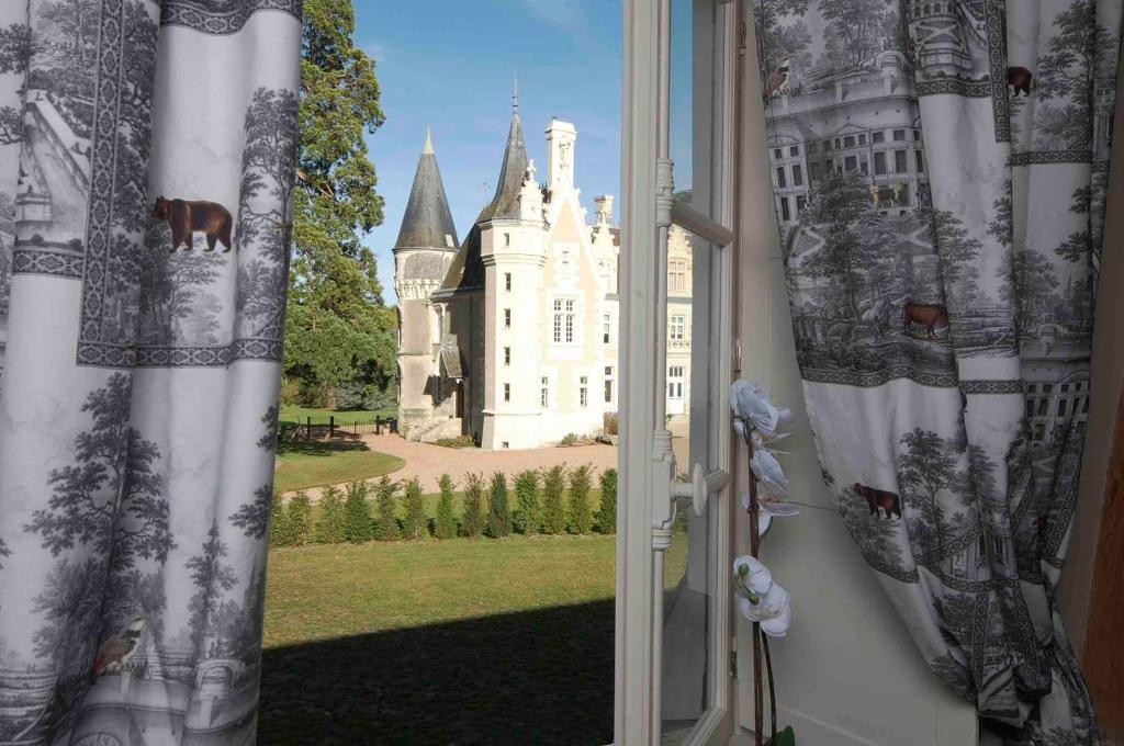 uma janela aberta com vista para um castelo em maison d'hôtes de l'orangerie 14 personnes em Azay-sur-Cher
