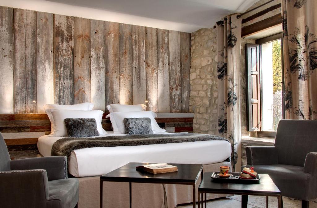 a bedroom with a bed and two chairs at La Maison du Passage - Chambres - Suites premium, Spa, Piscine et Restaurant in Martignargues