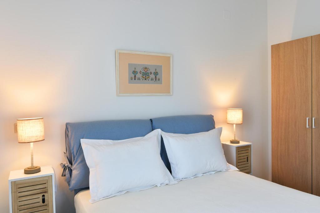 1 dormitorio con cama azul y almohadas blancas en Sifanto Mare Apartments, en Faros