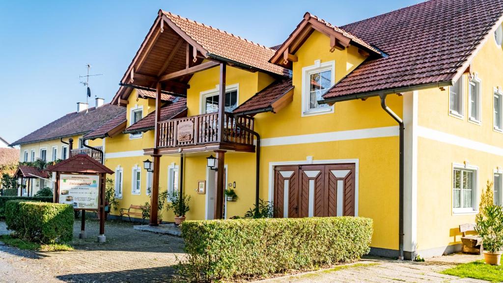 a yellow house with a balcony on a street at Salzingerhof in Kirchdorf am Inn