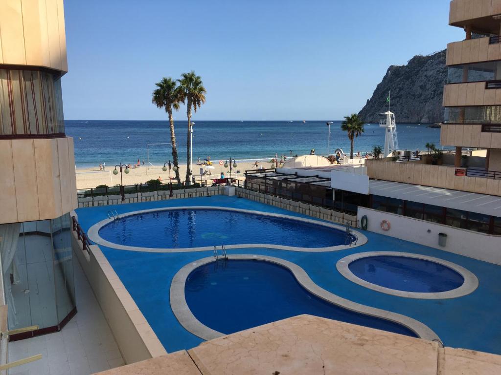a view of a swimming pool next to a beach at Apartamento en Calpe, playa de La Fossa, primera línea, AA in Calpe
