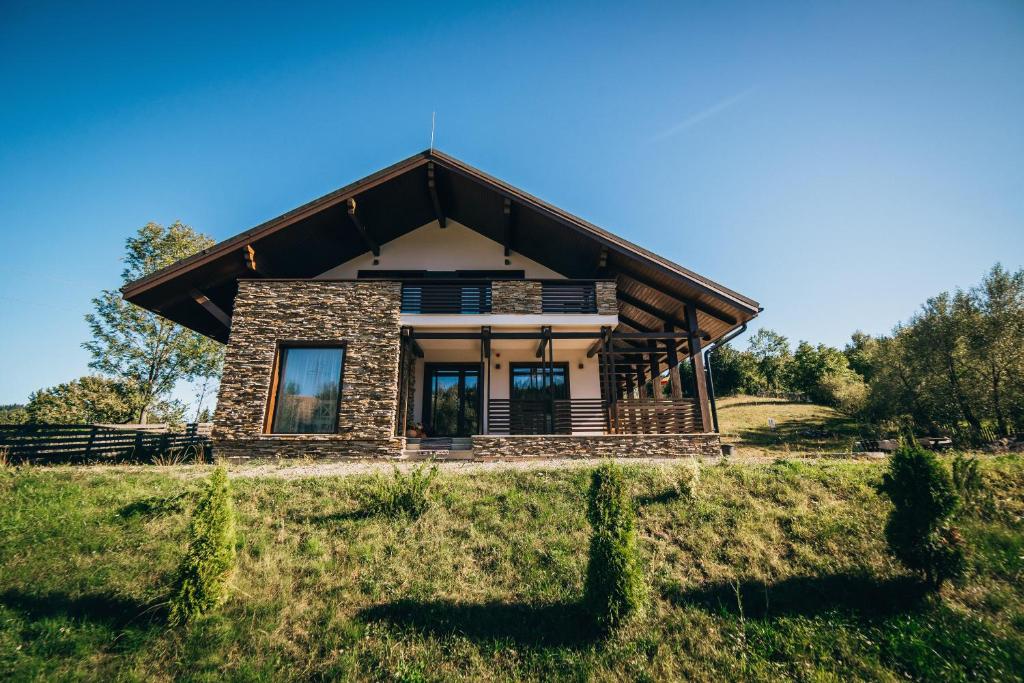 una casa en una colina con un campo de hierba en Casa De La Munte, en Mănăstirea Humorului