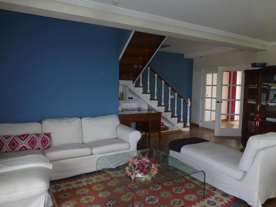 uma sala de estar com dois sofás brancos e uma parede azul em Casacovas em Ferrol