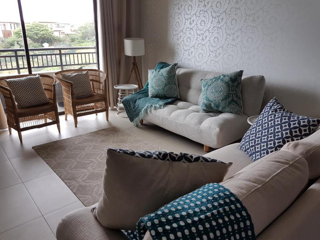 a living room with two couches and a balcony at Zimbali Suites 507 in Ballito