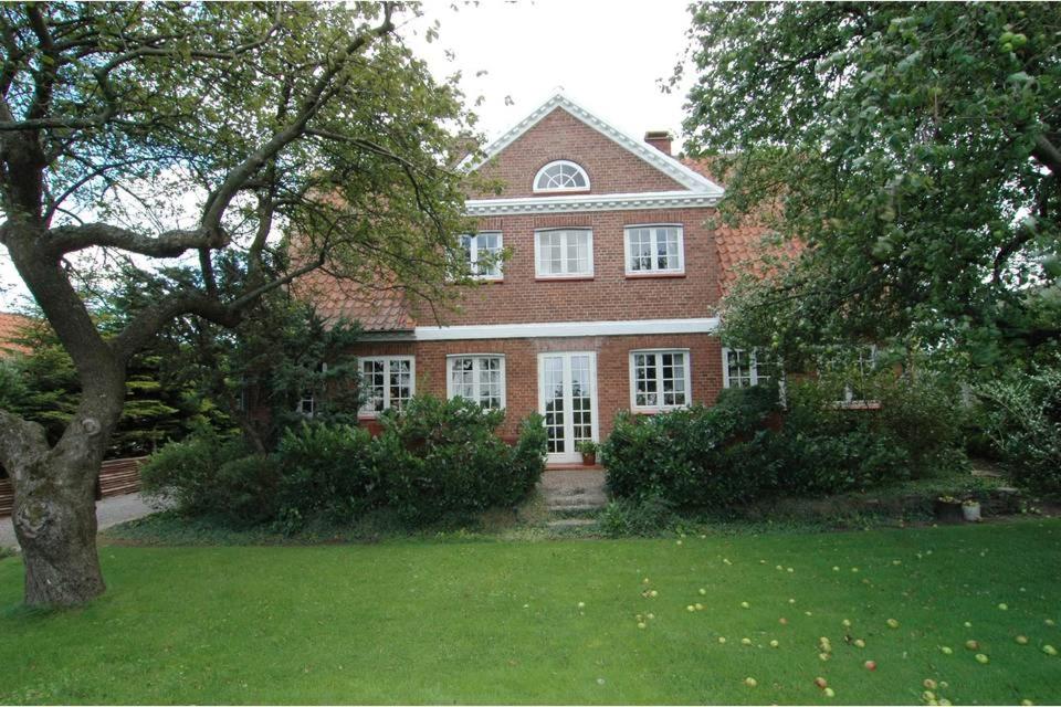 een groot rood bakstenen huis met een groene tuin bij Aakirkeby Bed and Breakfast in Åkirkeby