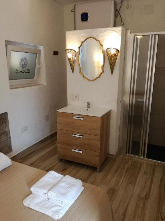 a bathroom with a sink and a mirror and a bed at La Mirilla Suites 2 in Tarifa
