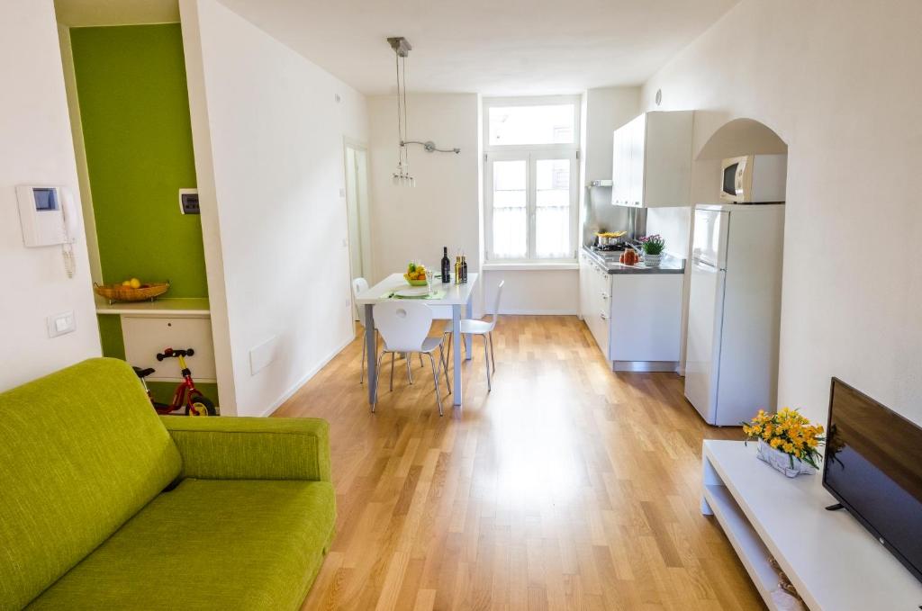 salon z zieloną kanapą i kuchnią w obiekcie Appartamenti Segantini w Arco