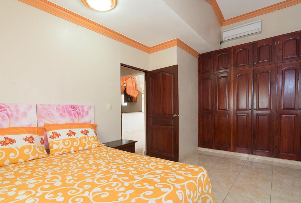 1 dormitorio con 1 cama grande y armarios de madera en Altagracia Apartments Santo Domingo, en Santo Domingo