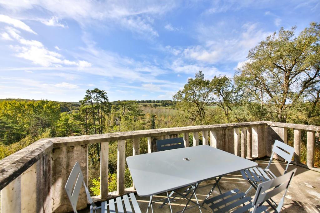 una mesa blanca y sillas en un balcón de madera en Belle vue, en Montsoreau