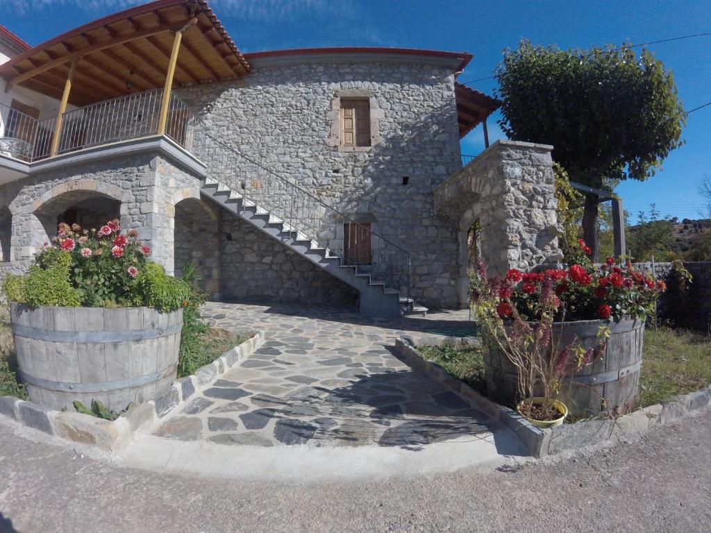 a stone house with a staircase and flowers in barrels at Stephania's Stone House in Karyes