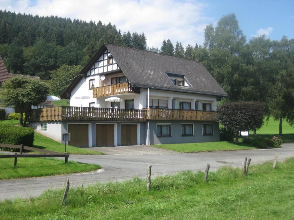 a large white house with a balcony on a road at Pension-Gästehaus Waldhof in Winterberg