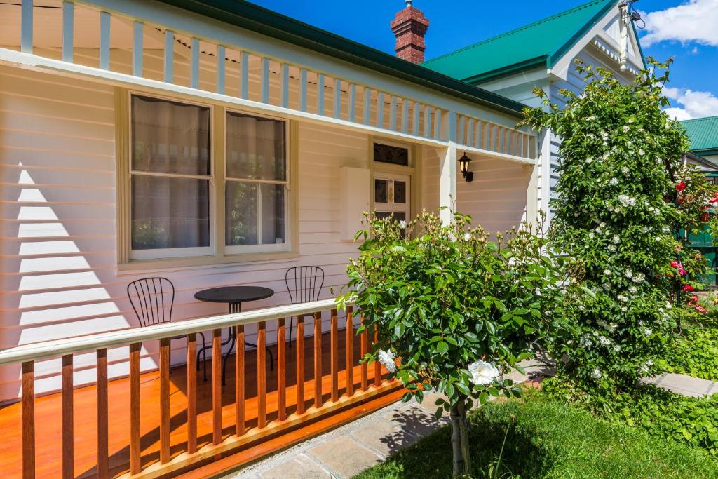 um alpendre frontal de uma casa com uma mesa e cadeiras em Rosehaven Cottage em Hobart