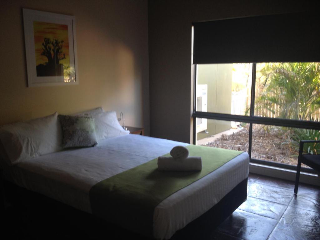 a bedroom with a bed and a large window at Breezes Apartments in Broome