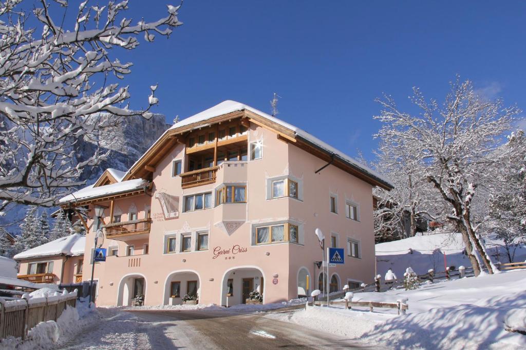 a large building with snow on the ground at Garni Criss in Colfosco