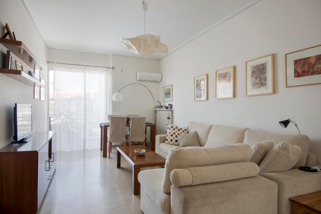 ein Wohnzimmer mit einem Sofa und einem Tisch in der Unterkunft Varkiza Apartment in Varkiza
