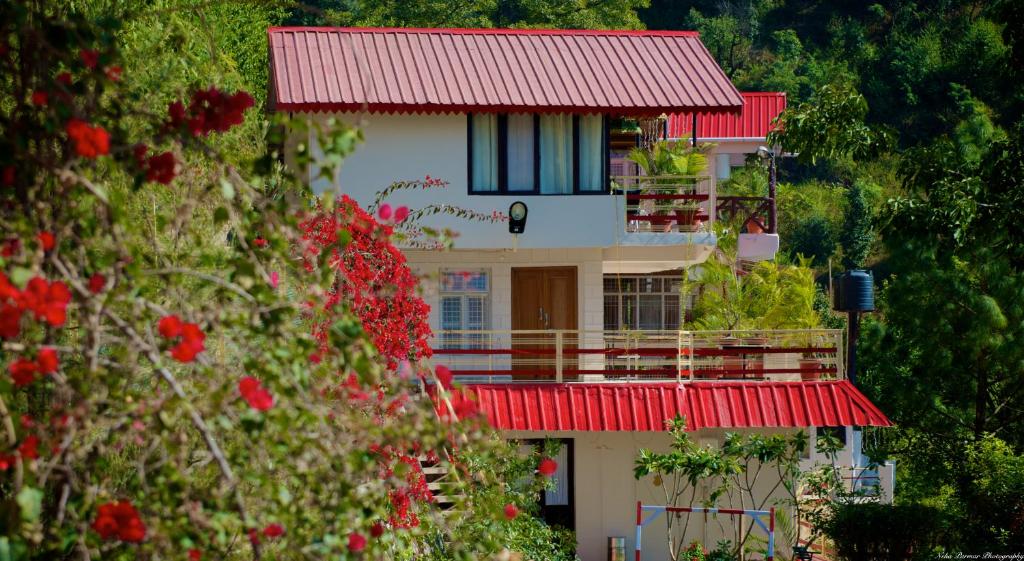 ein Gebäude mit rotem Dach und ein paar roten Blumen in der Unterkunft Magpie Retreat in Bhīm Tāl