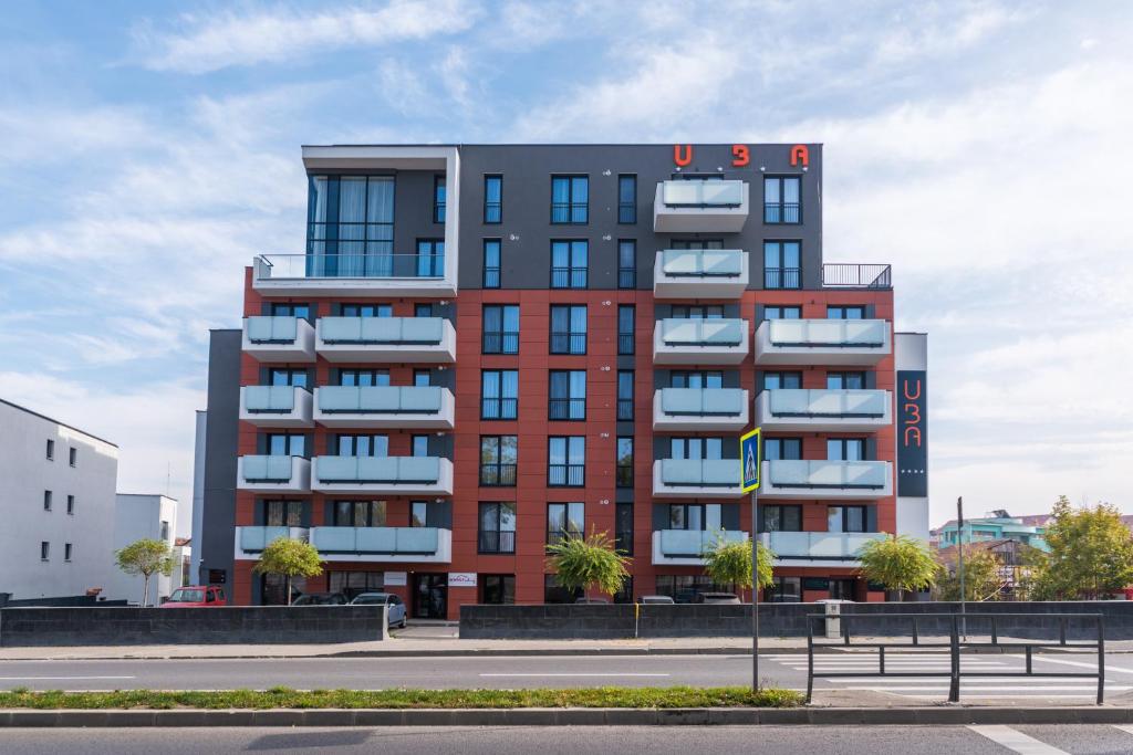 un edificio alto de color rojo con balcones en una calle en UBA Accommodation Aparthotel, en Cluj-Napoca