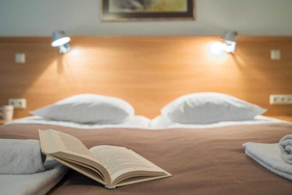 a bed with an open book on it with pillows at Guest House Milda in Druskininkai