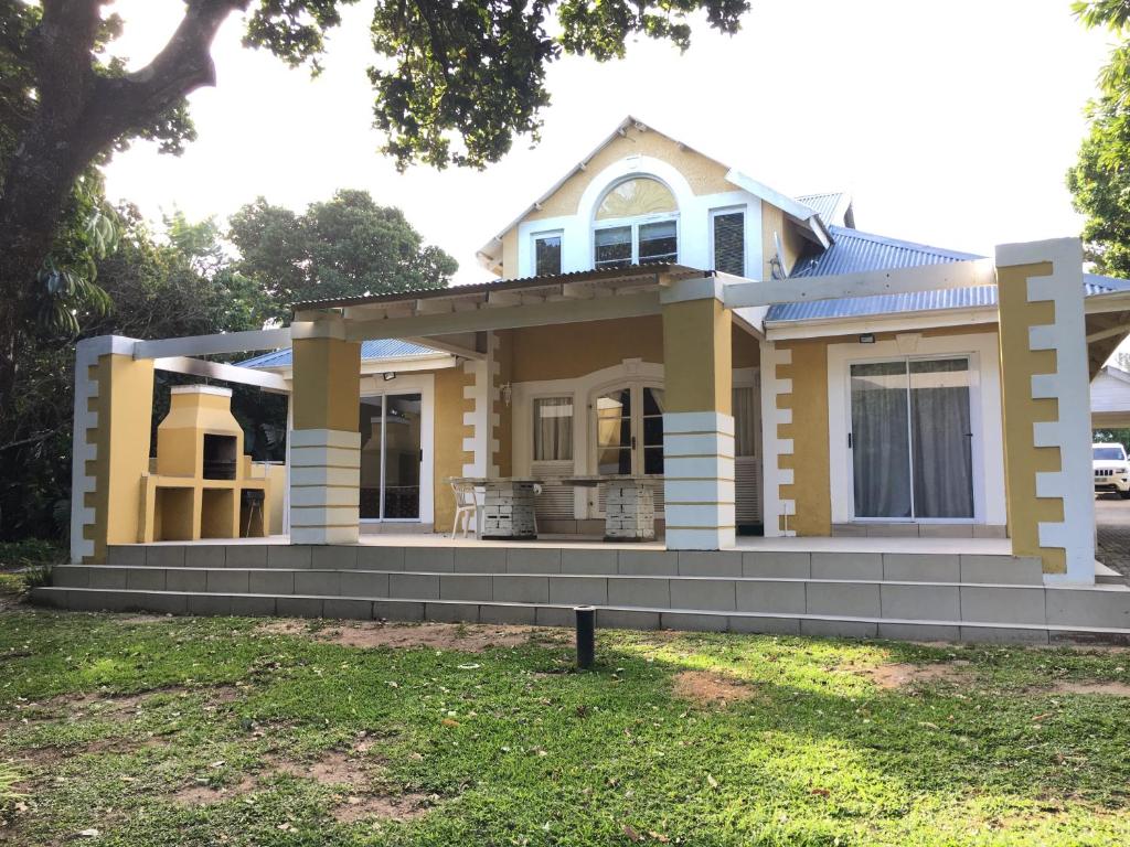 a small yellow house with a front yard at Caribbean Estates Villa B10 on Barbados in Port Edward