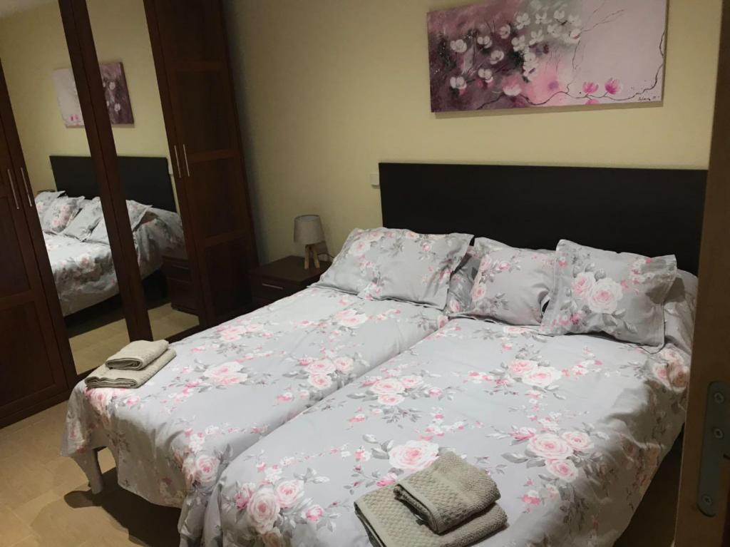 ラス・ナバス・デル・マルケスにあるApartamento La Palomaのベッドルーム1室(ピンクの花が咲くベッド1台付)