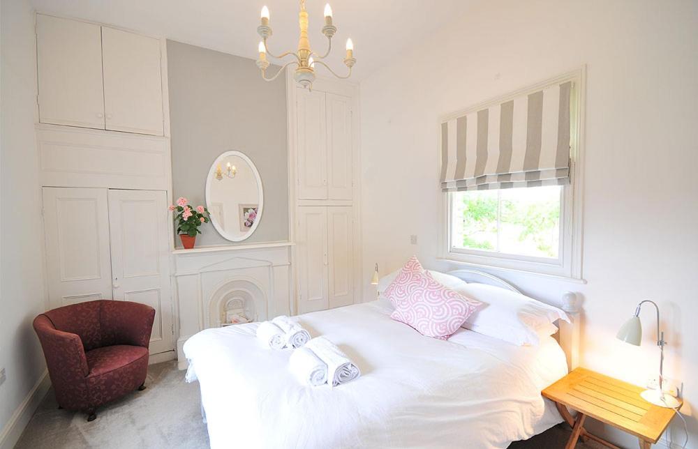 a white bedroom with a bed and a chair at Poplars Farm in Henlow