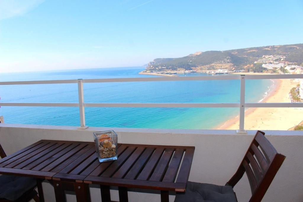 a wooden bench sitting on a balcony overlooking a beach at Akisol Sesimbra Beach in Sesimbra