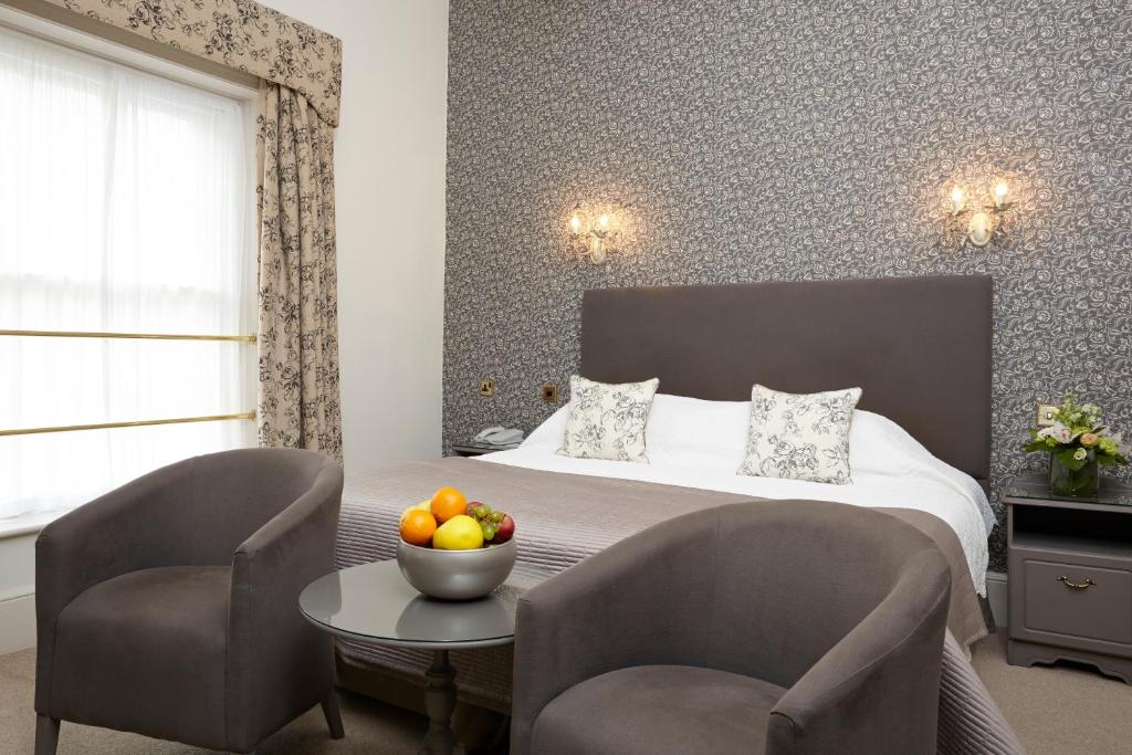 a hotel room with a bed and two chairs and a table at The Royal Hotel in Ventnor