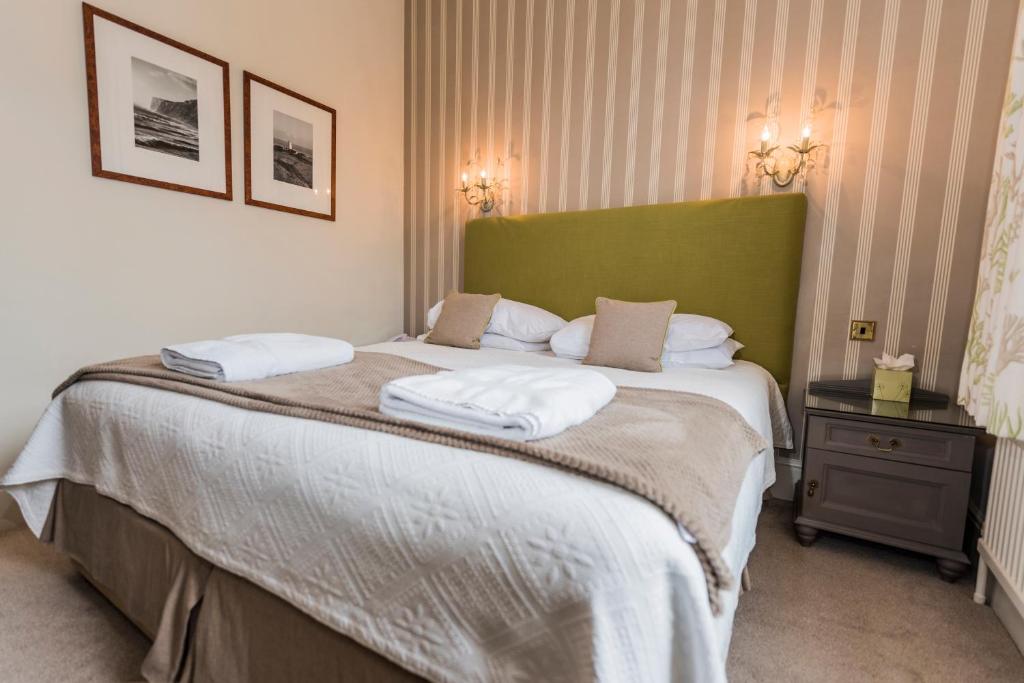 a bedroom with a large bed with a green headboard at The Royal Hotel in Ventnor