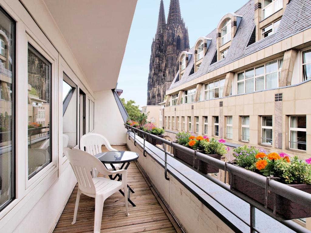 a balcony with two chairs and a table and a window at Callas am Dom in Cologne