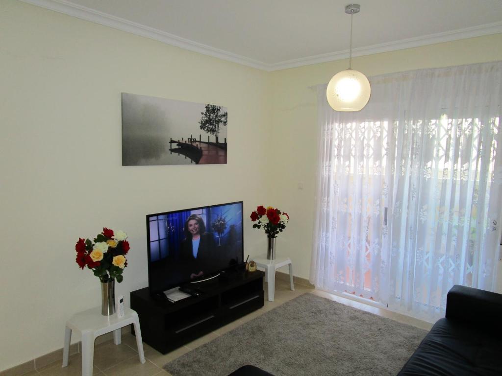 a living room with a flat screen tv and flowers at Jardin de Alba in Villacosta