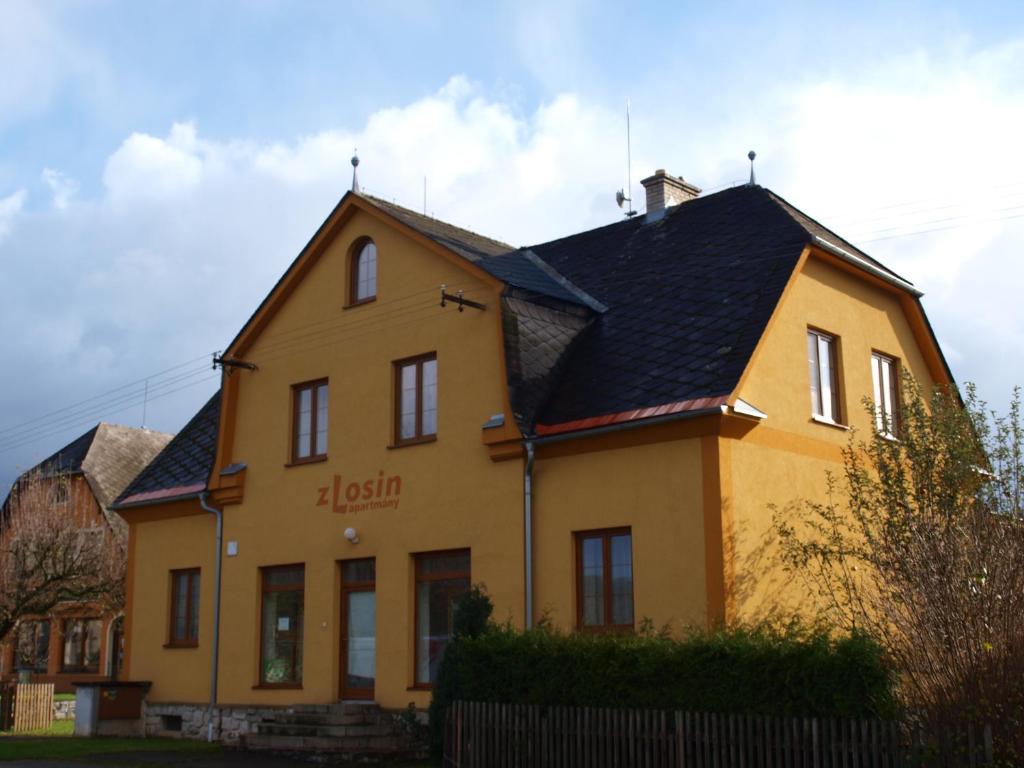 une maison jaune avec un toit noir dans l'établissement Apartmány zLosin, à Velké Losiny