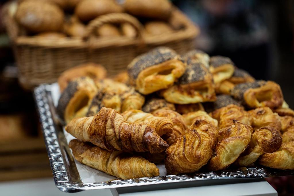 a pile of pastries on a tray with a basket of bread at Absalon Hotel in Copenhagen