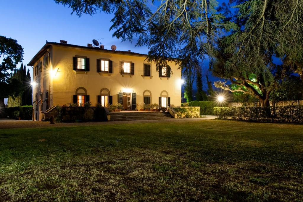 una casa con luces encendidas en un patio por la noche en Villa Il Padule en Bagno a Ripoli