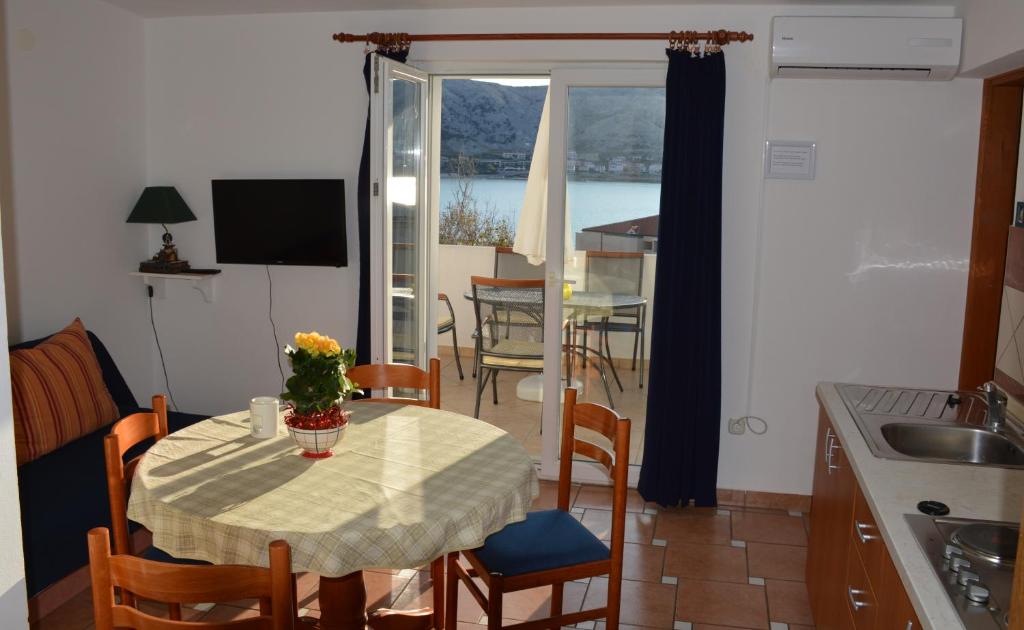 a kitchen with a table with a vase of flowers on it at Apartments Burcul Pag in Pag